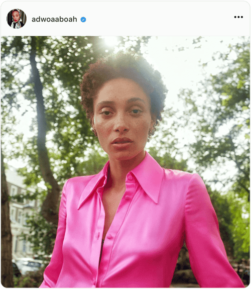 Portrait of influencer Adwoa Aboah wearing a birhgt pink blouse in a park
