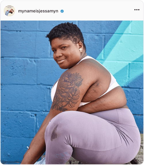 Side profile of influencer Jessamyn Stanley sitting in front of a blue wall