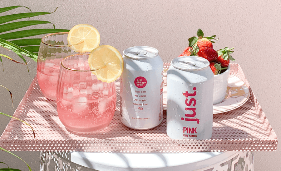 Two cans of soda next to two full glasses on a pink tray