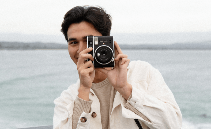 Man holds a camera and smiles while taking a photo