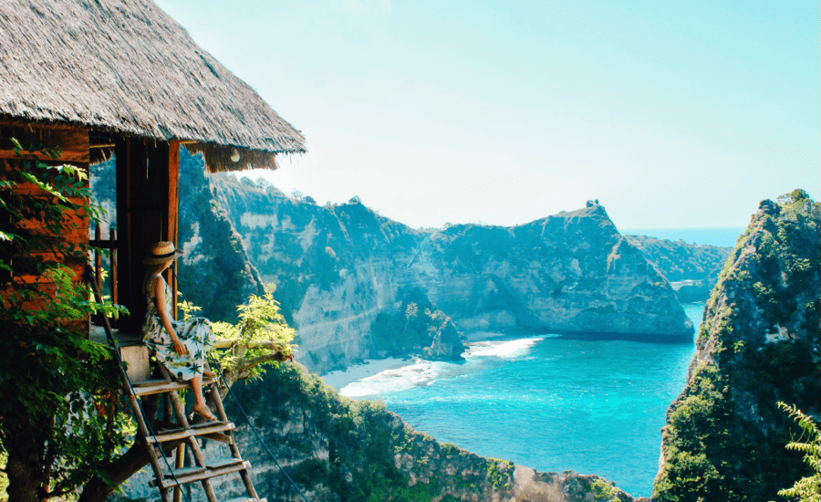 Woman sitting on stairway to hut looks out onto grand vista