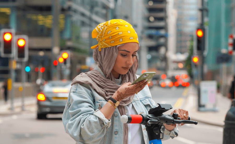 Woman looks at phone in front of busy street