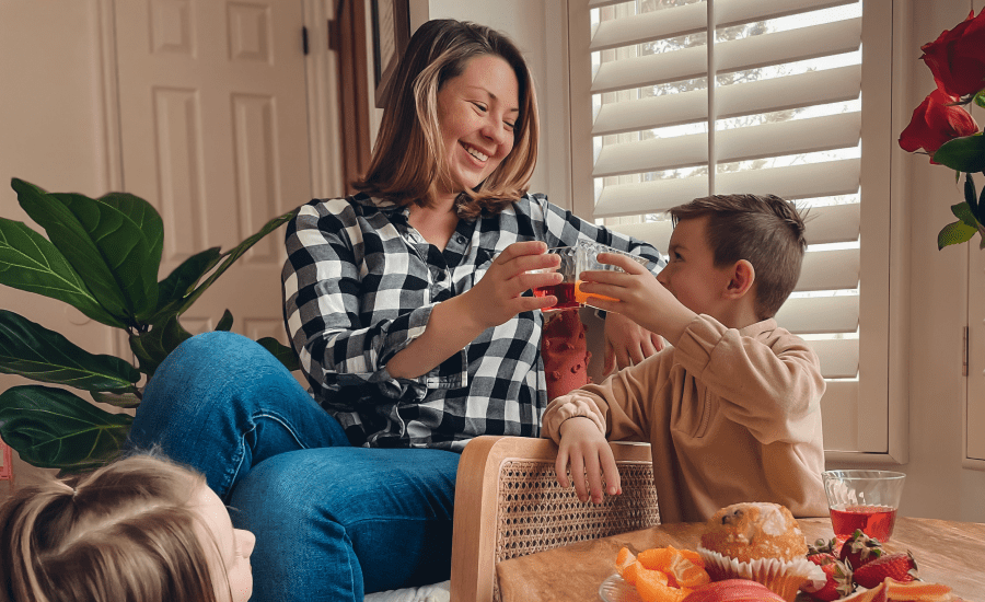 mother and son cheers glasses while smiling and looking at one another