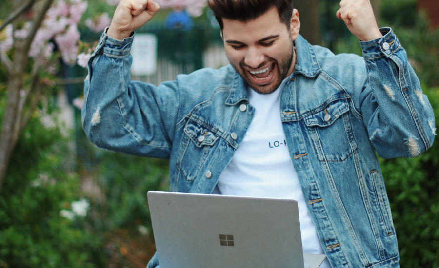 A happy and excited man working on a laptop