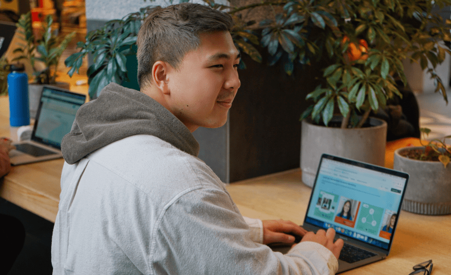 man smiles while working on his laptop