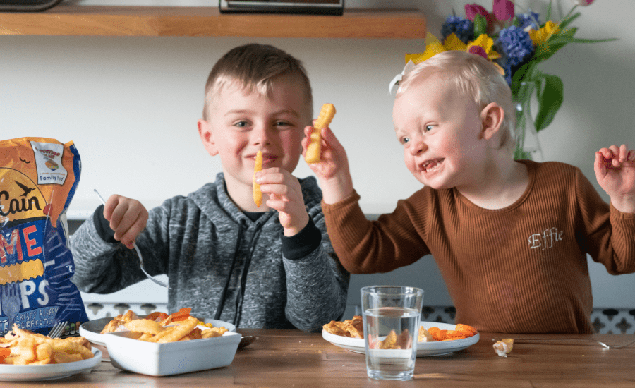 Two children hold up fries while smiling