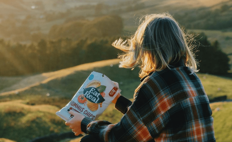 woman eats chips while looking out on a landscape