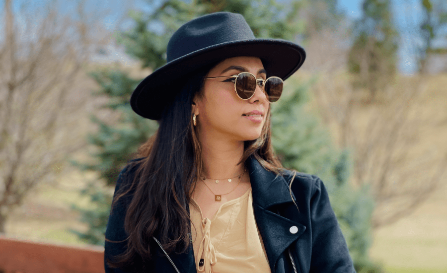 woman in black hat and sunglasses looks wistfully to the right